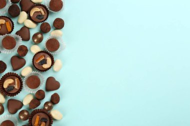 Açık mavi arka planda farklı lezzetli çikolata şekerlemeleri, düz yatış. Metin için boşluk