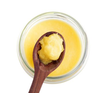 Cam kavanoz ve kaşık dolusu Ghee yağı beyaza izole edilmiş.