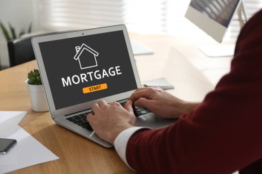 İpotek konsepti. Sofrada modern laptop kullanan adam, yakın plan.