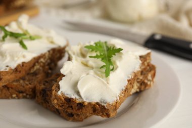 Krem peynirli ekmek ve roka tabakta, yakın plan.