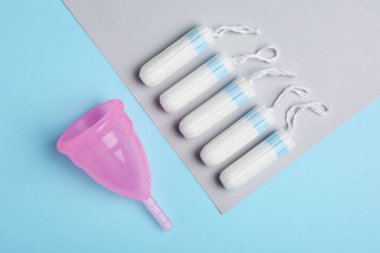 Regl bardağı ve tampon rengi arka planda, düz yerde.