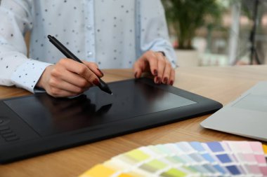 Ahşap masada grafik tableti olan profesyonel tasarımcı, yakın plan.