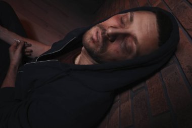 Aşırı dozda uyuşturucu bağımlısı adam tuğla duvarın yanında.