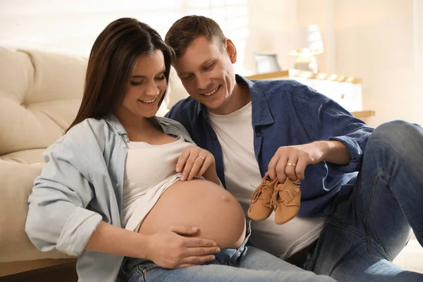 Jonge Zwangere Vrouw Haar Man Met Baby Schoenen Thuis — Stockfoto