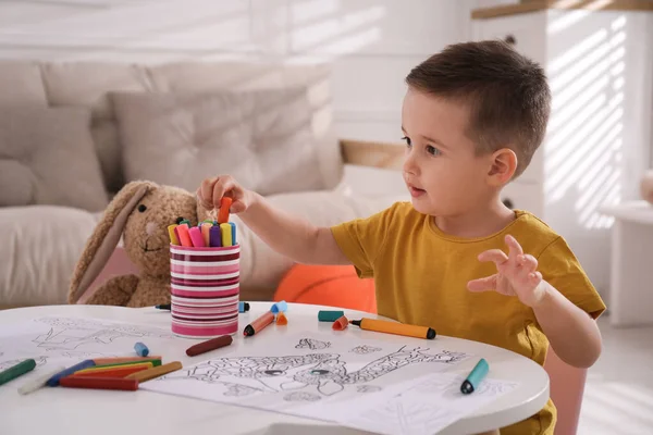 Cute child coloring drawing at table in room