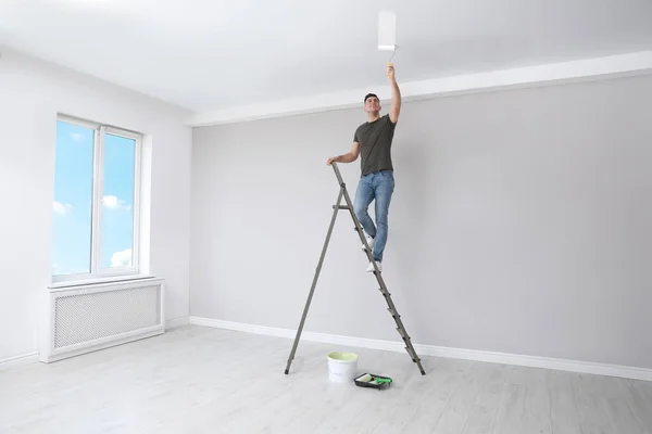 Mann Bemalt Decke Mit Roller Auf Leiter Zimmer — Stockfoto