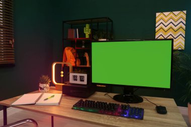 Modern bilgisayar ve RGB klavyesi ahşap masa içinde. Mokup yeşil ekran