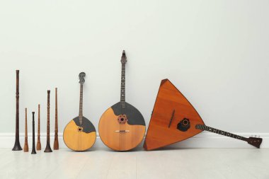 Beyaz duvarın yanında farklı ahşap müzik aletleri var.