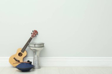 Beyaz duvarın yanında Ukulele ve davullar, yazı için yer. Müzik aletleri