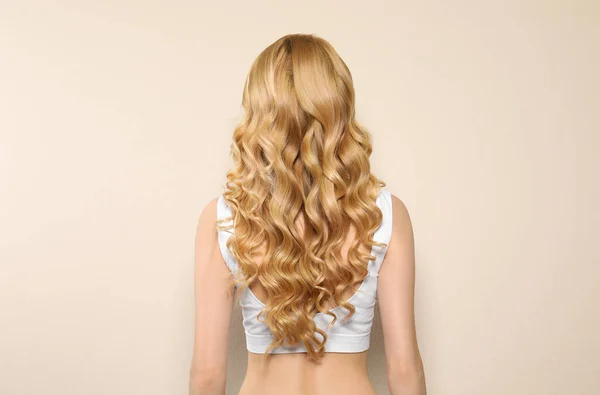 Uzun Kıvırcık Saçlı Bej Arka Planda Genç Bir Kadın — Stok fotoğraf