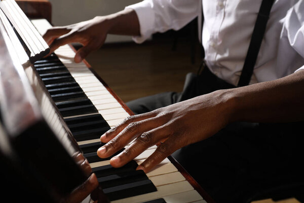 Афроамериканец играет на пианино в помещении, крупным планом. Талантливый музыкант