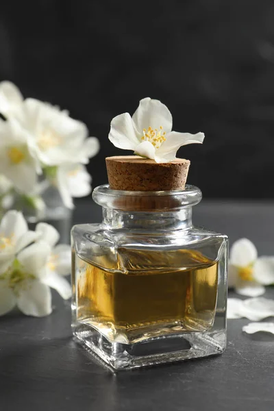 Ätherisches Jasminöl Und Frische Blumen Auf Dunkelgrauem Tisch — Stockfoto