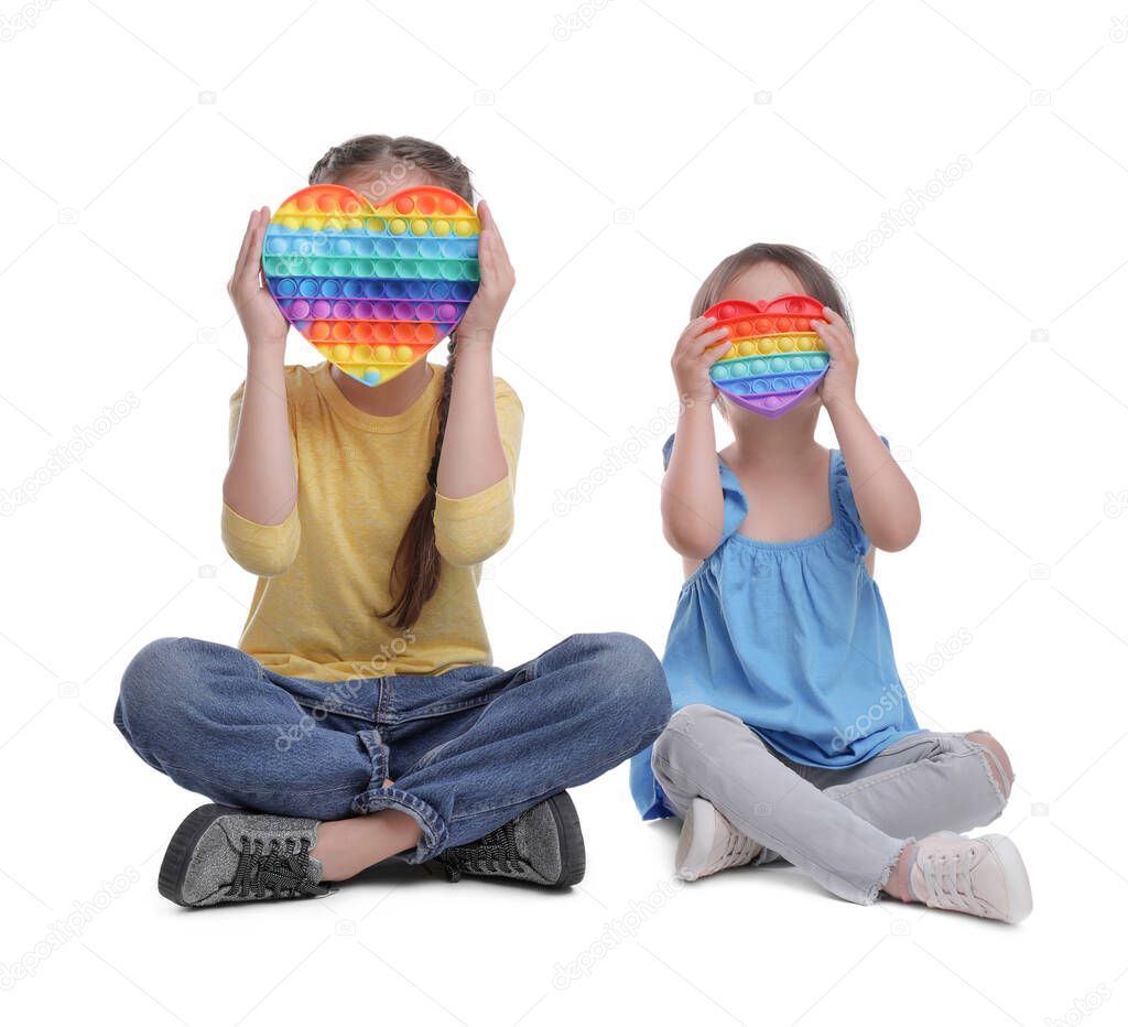 Little girls with pop it fidget toys on white background
