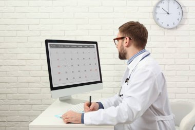 Klinikteki masada bilgisayarla çalışan çocuk doktoru.
