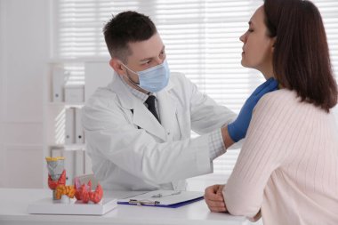 Hastanedeki hastanın tiroit bezini inceleyen doktor.