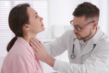 Hastanedeki hastanın tiroit bezini inceleyen doktor.