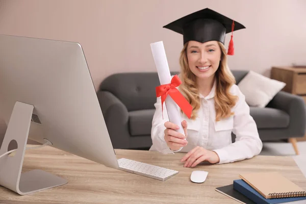 Happy student with graduation hat at workplace in office, focus on diploma