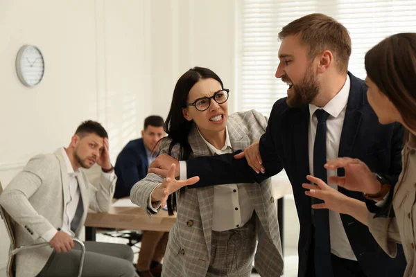 Man interrupting colleagues fight at work in office