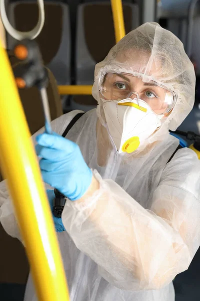 Public transport sanitation. Worker in protective suit disinfecting bus salon