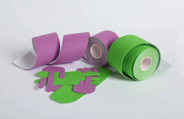 Bright kinesio tape rolls and pieces on light background