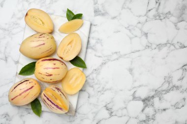 Beyaz mermer masa üzerinde yeşil yapraklı karpuz dilimleri, üst manzara. Metin için boşluk