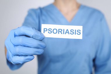 Açık gri arkaplanda PSORIASIS yazılı kart tutan doktor, yakın plan