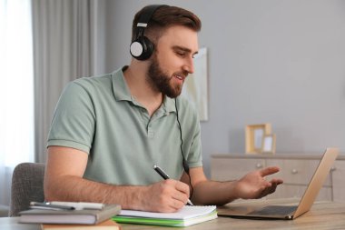 İçerideki masada internetteki web sitesinde notlar alan genç bir adam.