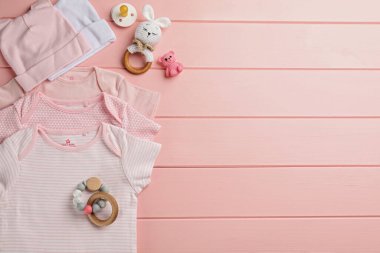 Bebek kıyafetleri ve aksesuarları pembe ahşap arka planda düz kompozisyon, metin için boşluk
