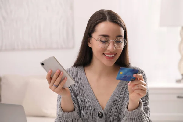 持信用卡的妇女在室内使用智能手机进行网上购物 — 图库照片