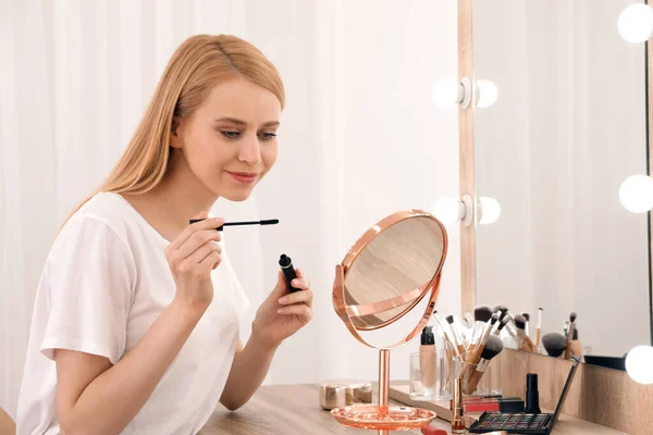 部屋の中で鏡の近くに化粧を適用する美しい女性 — ストック写真