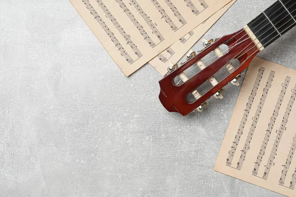 Composition with guitar and music notations on light table, flat lay. Space for text