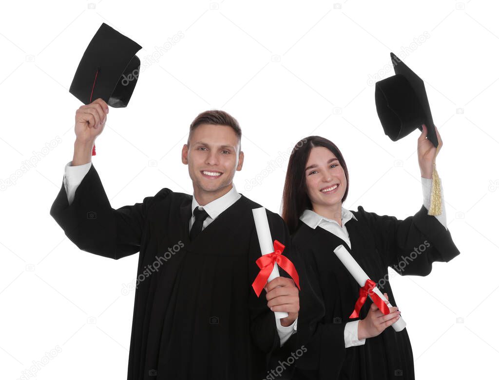 Happy students in academic dresses with diplomas on white background