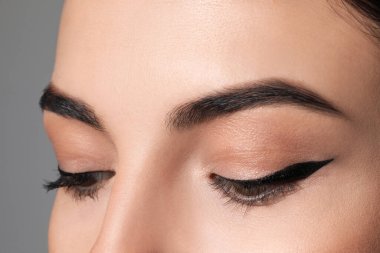 Gri arka planda siyah göz kalemi olan güzel kadın, yakın plan.