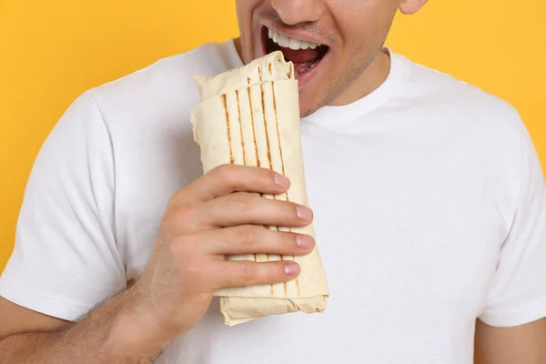 Man Äter Läckra Shawarma Gul Bakgrund Närbild — Stockfoto