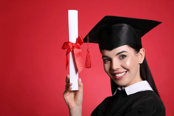 赤い背景に卒業帽子と卒業証書を持つ幸せな学生 テキストのスペース — ストック写真