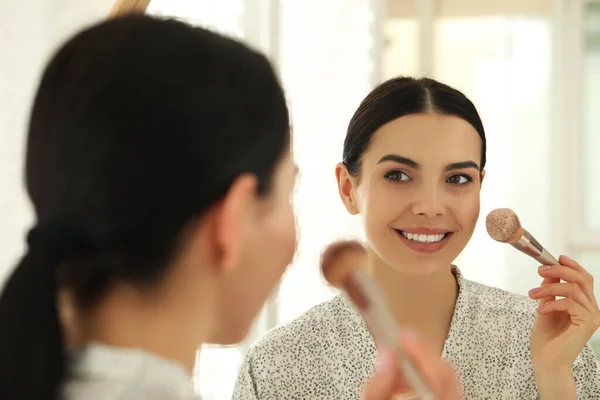 Vacker Ung Kvinna Tillämpa Ansiktspulver Med Borste Framför Spegeln Hemma — Stockfoto