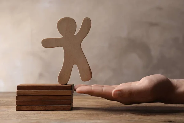 Woman holding human figure near wooden blocks at table, closeup