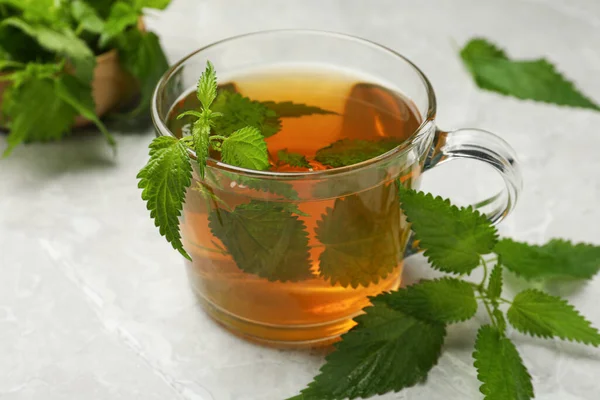 Glas Kopp Aromatisk Nässla Och Gröna Blad Ljusgrå Bord Närbild — Stockfoto