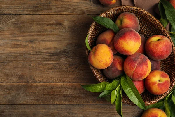 Fresh ripe juicy peaches on wooden table, flat lay. Space for text