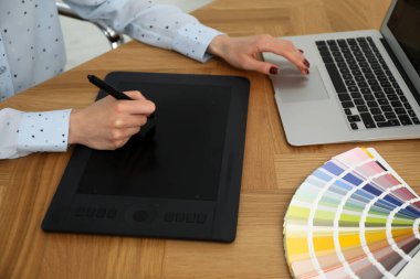 Ahşap masada grafik tableti olan profesyonel tasarımcı, yakın plan.