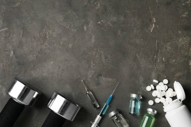 Farklı uyuşturucular, spor aletleri ve gri masadaki yazı için yer. Doping kontrolü