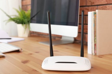 Tahta masadaki bilgisayarın yanında modern Wi-Fi yönlendirici