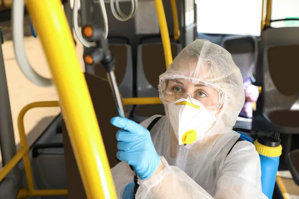 Public transport sanitation. Worker in protective suit disinfecting bus salon