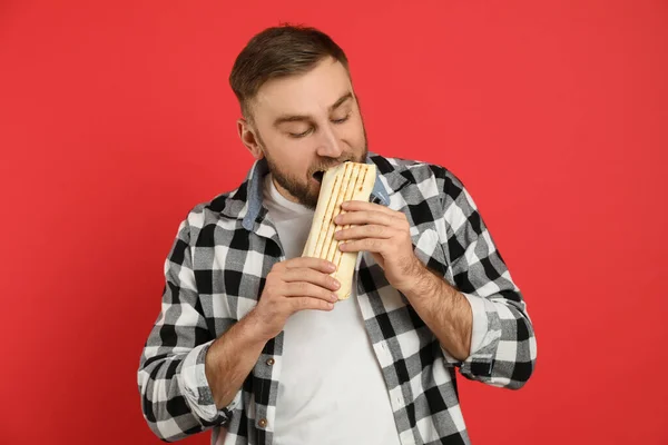 Young Man Eating Delicious Shawarma Red Background — Stock Photo, Image