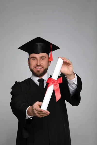 Gelukkige Student Met Afstudeerhoed Tegen Grijze Achtergrond Focus Diploma — Stockfoto