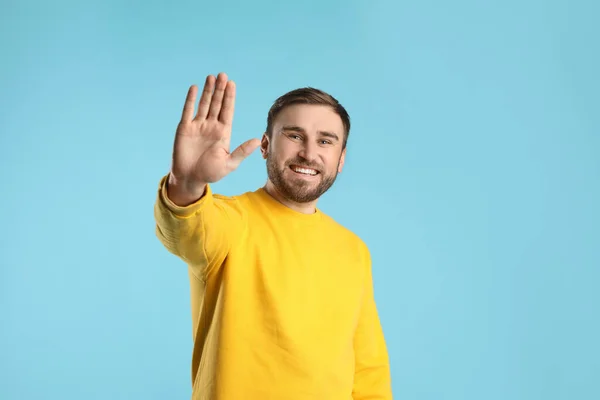 Jovem Feliz Acenando Para Dizer Olá Fundo Azul Claro — Fotografia de Stock