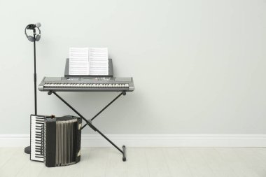 Elektronik sentezleyici, akordeon ve mikrofon beyaz duvarın yanında, mesaj için yer var. Müzik aletleri