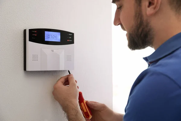 Man installing home security system on white wall in room, closeup