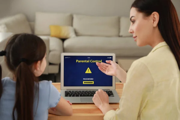 Mother installing parental control app on laptop to ensure her child\'s safety at home