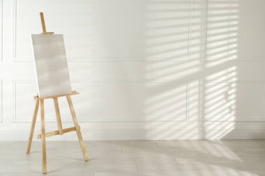 Işık duvarının yanında boş tuval olan ahşap sehpa. Metin için boşluk